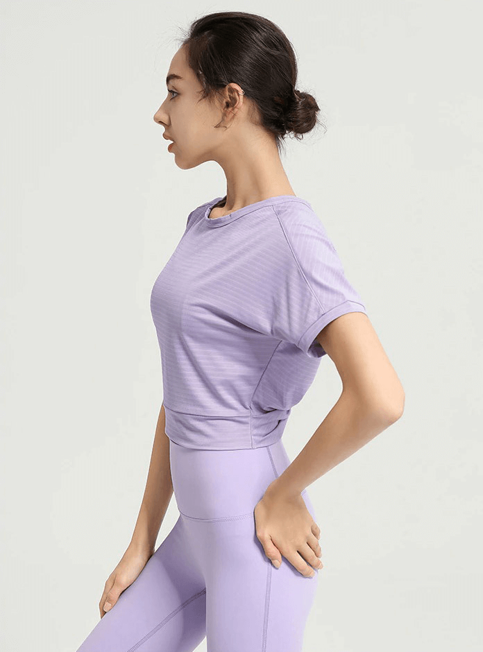 Woman wearing a stylish purple backless crop top for gym sportswear, showcasing its comfortable fit and durable fabric for active lifestyles.